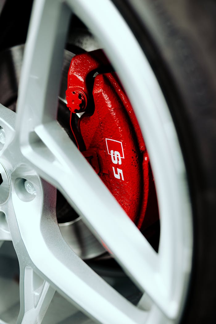 Macro shot of a red brake caliper and alloy wheel showcasing automotive engineering.