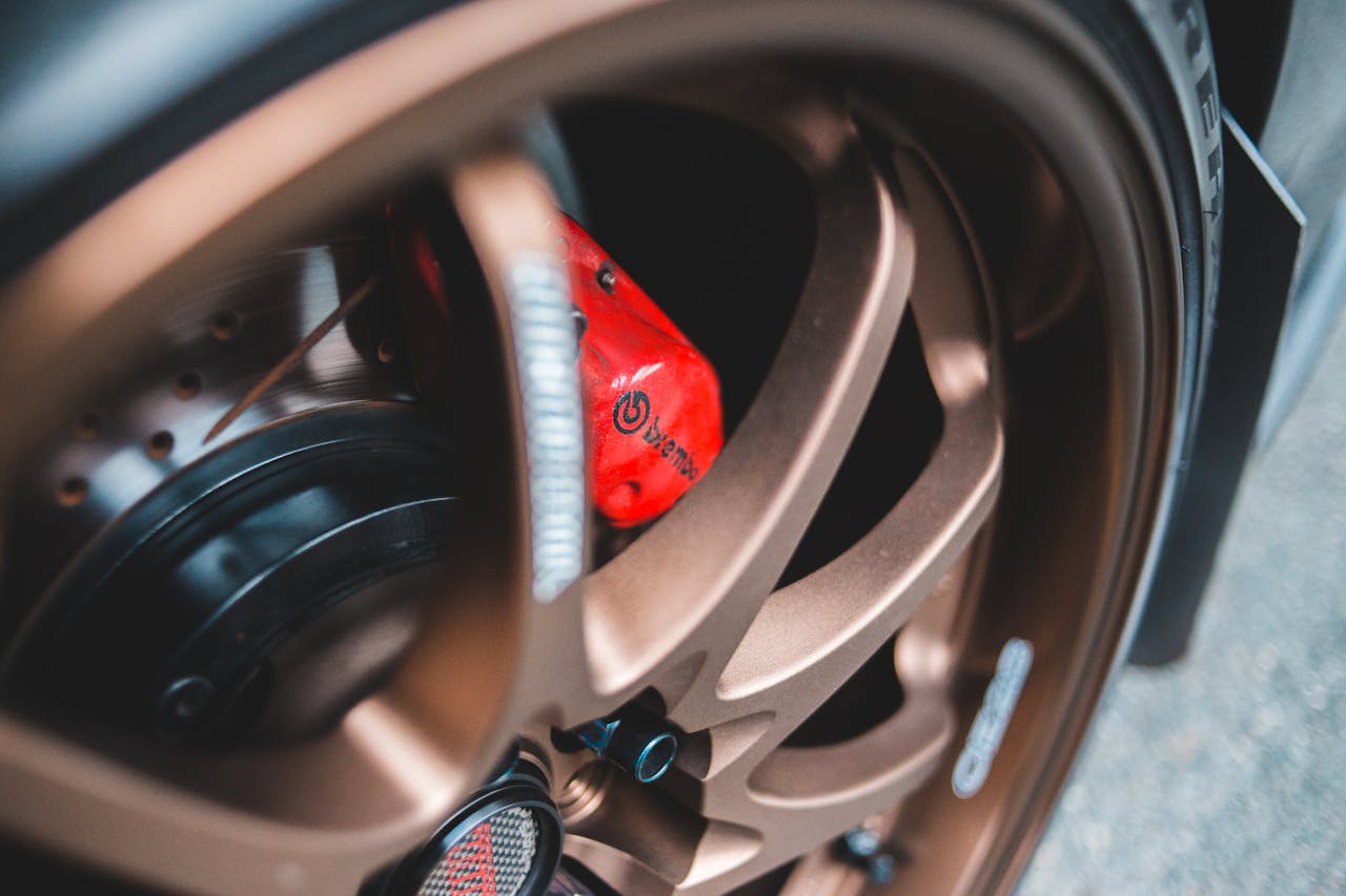 Closeup of metallic beige round wheel of automobile parked on paved street in daylight